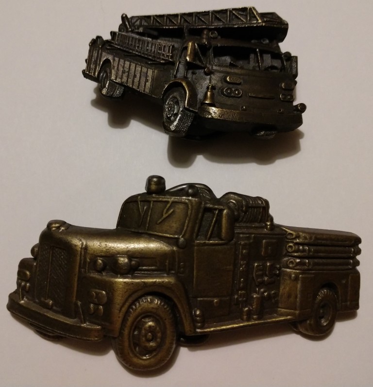Two metal belt buckles which depict three dimensio